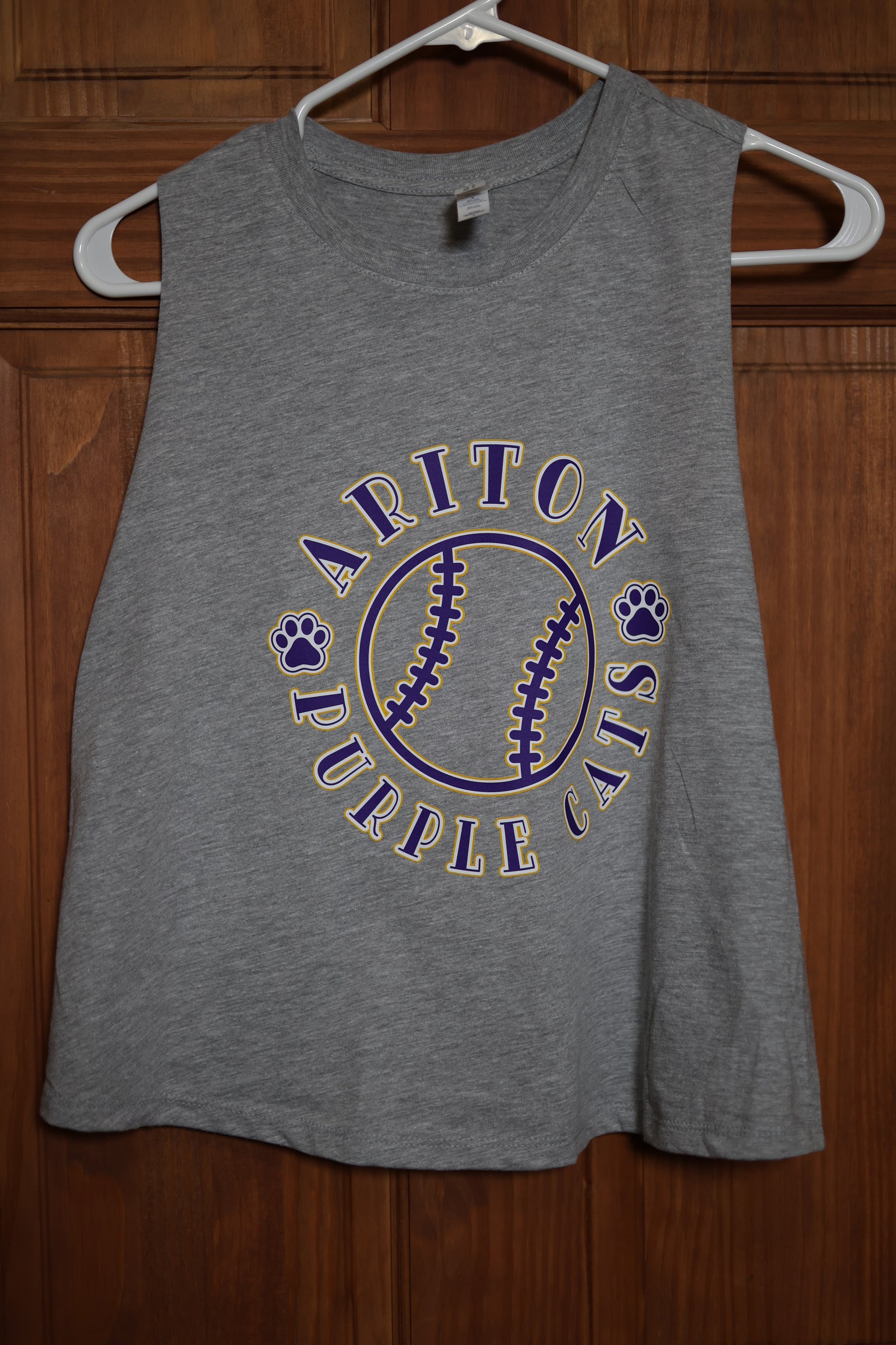 Gray muscle tank featuring a custom circular team design with a baseball graphic, paw prints, and Ariton Purple Cats lettering in purple and gold.